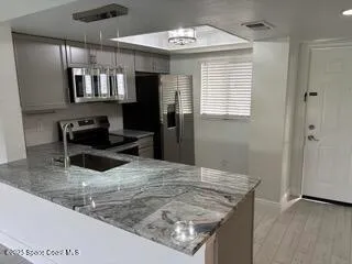 a view of a kitchen with kitchen island a sink wooden floor and a refrigerator