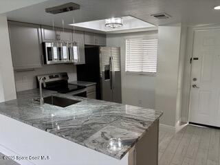 1704 University Lane, Unit 703 Cocoa, FL 32922 - Photo 3 of 18 a view of a kitchen with kitchen island a sink wooden floor and a refrigerator