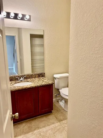 a bathroom with a granite countertop toilet and a sink