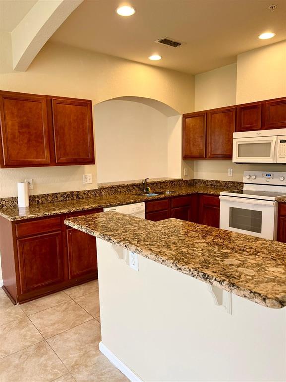 2992 Langdon Lane South Kissimmee, FL 34741 - Photo 13 of 39 a kitchen with stainless steel appliances granite countertop a stove a sink and a refrigerator