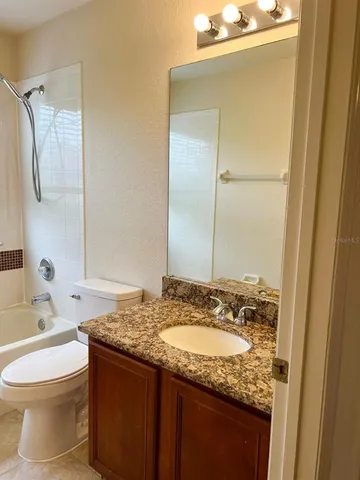a bathroom with a granite countertop sink toilet and shower