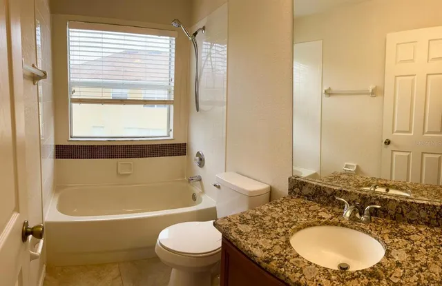 a bathroom with a granite countertop sink toilet mirror and bathtub