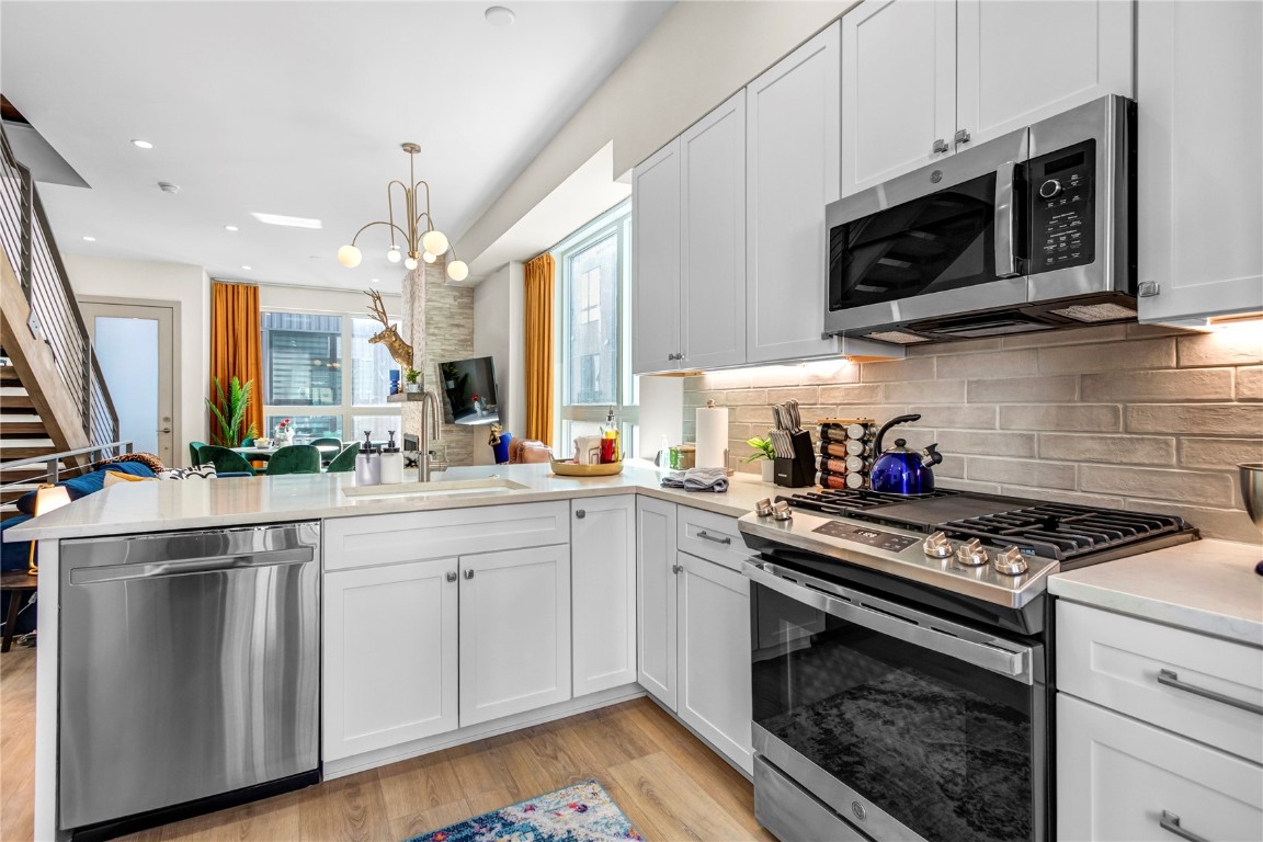 58 3rd Street, Unit D Silverthorne, CO 80498 - Photo 4 of 29 a kitchen with stainless steel appliances a sink a stove a microwave and wooden cabinets