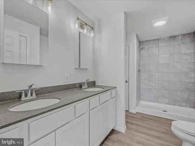 a bathroom with a granite countertop sink a toilet and shower
