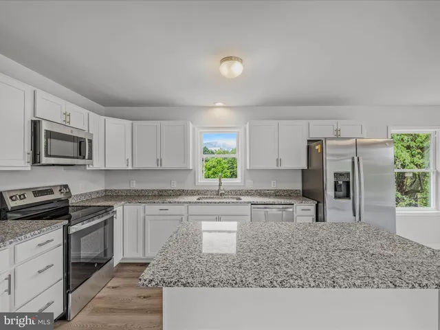 a kitchen with a sink a counter top space stainless steel appliances and cabinets