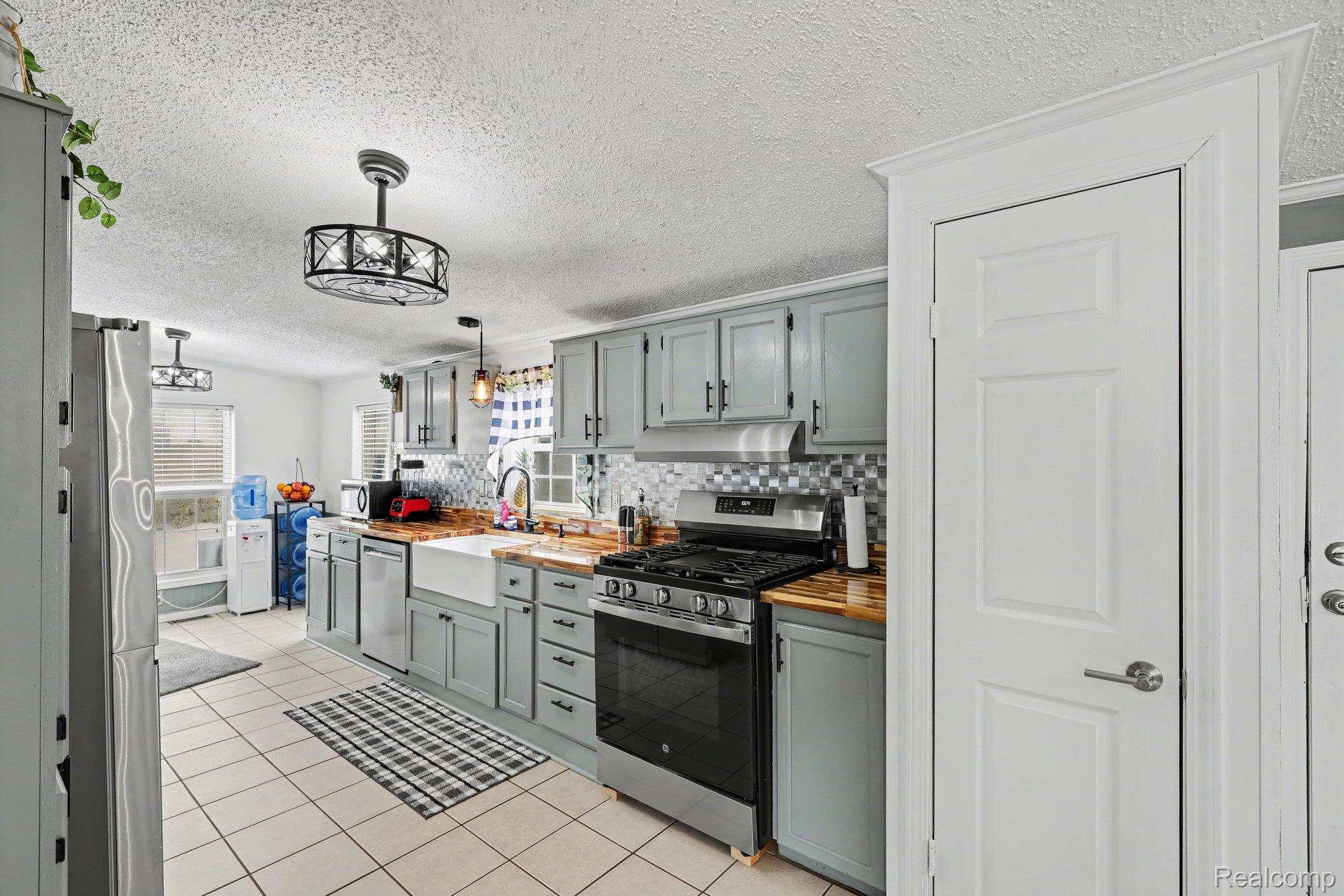 4458 Palms Road Casco, MI 48064 - Photo 12 of 32 Kitchen featuring wooden counters, gray cabinetry, stainless steel appliances, tasteful backsplash, and a textured ceiling