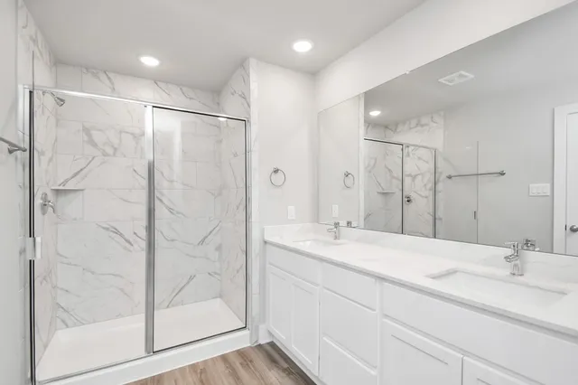 a bathroom with a double vanity sink mirror and shower