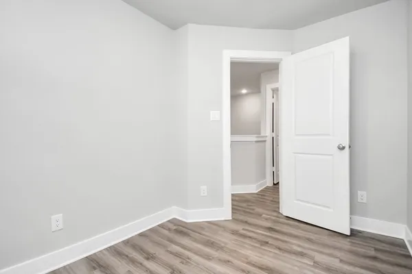 a view of an empty room with wooden floor and closet