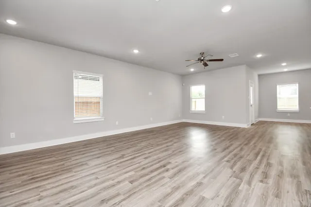 an empty room with wooden floor and windows