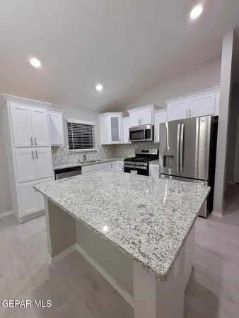 a kitchen with kitchen island granite countertop a sink refrigerator and microwave
