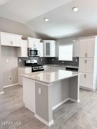 a kitchen with stainless steel appliances granite countertop a stove top oven a sink a refrigerator and white cabinets