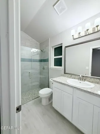 a bathroom with a granite countertop sink toilet a mirror a vanity and shower