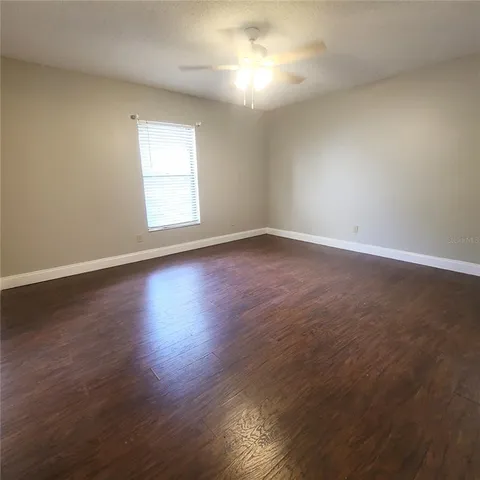 a view of an empty room with wooden floor and a window