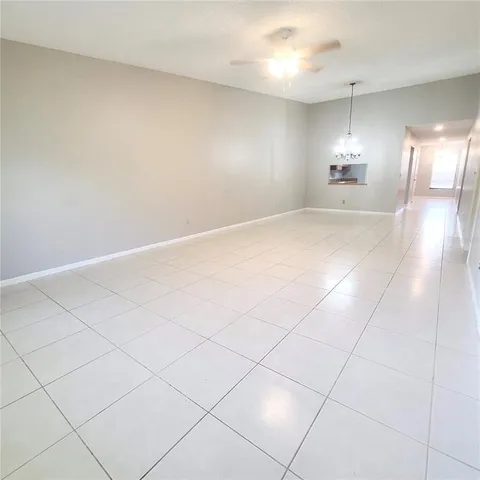 an empty room with kitchen view and windows