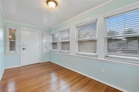 a view of empty room with wooden floor and windows