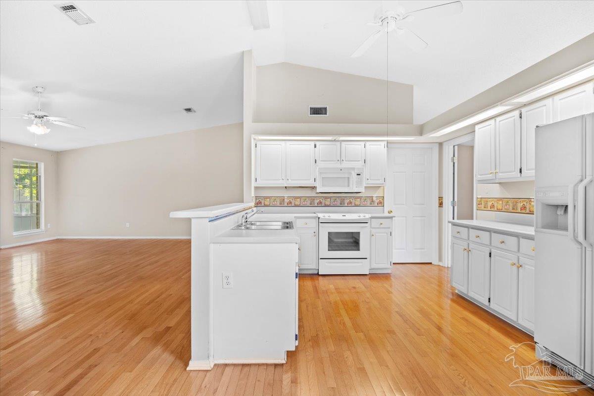 3485 Ashmore Lane Pace, FL 32571 - Photo 15 of 49 a kitchen with wooden floors and white appliances