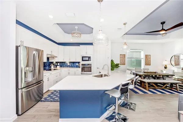a living room with stainless steel appliances kitchen island granite countertop a sink and a refrigerator
