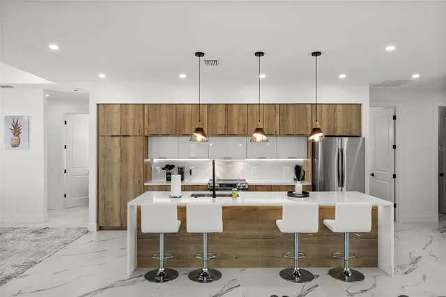 a kitchen with stainless steel appliances kitchen island granite countertop a refrigerator and a stove top oven with white cabinets