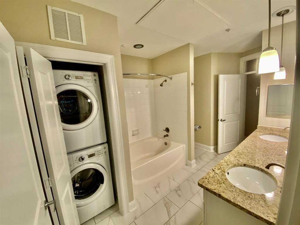 a bathroom with a granite countertop sink and a washing machine