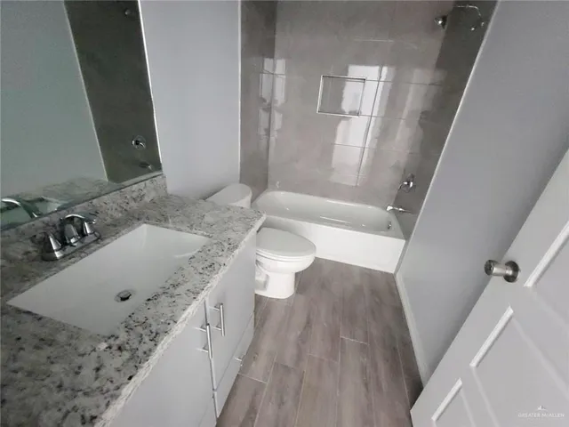 a bathroom with a granite countertop sink a toilet and shower