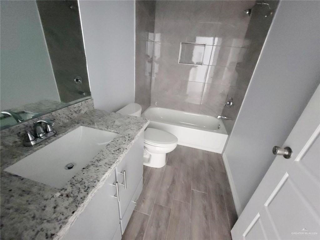 2808 Rosemary Drive, Unit 1 Weslaco, TX 78599 - Photo 11 of 13 a bathroom with a granite countertop sink a toilet and shower