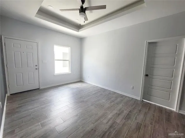 an empty room with wooden floor fan and windows