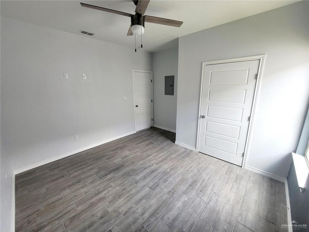 2808 Rosemary Drive, Unit 1 Weslaco, TX 78599 - Photo 6 of 13 an empty room with wooden floor cabinet and windows