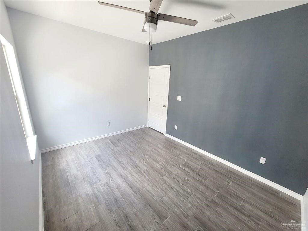 2808 Rosemary Drive, Unit 1 Weslaco, TX 78599 - Photo 7 of 13 wooden floor in an empty room with a window