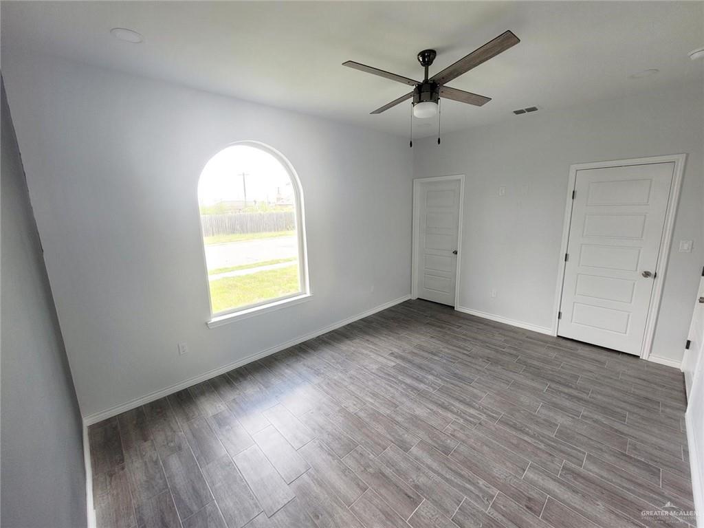 2808 Rosemary Drive, Unit 1 Weslaco, TX 78599 - Photo 8 of 13 an empty room with wooden floor chandelier fan and windows