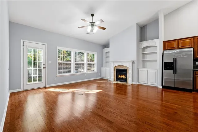 a view of an empty room with wooden floor fireplace and a window