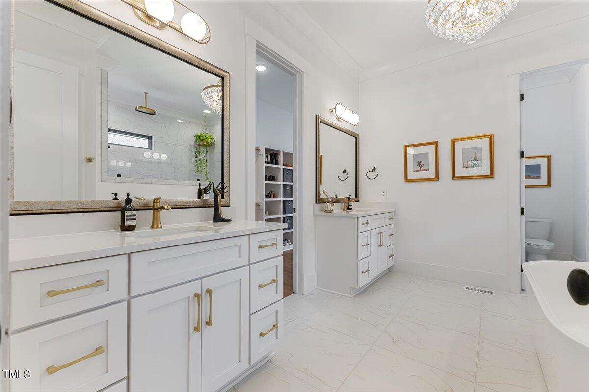 8420 Bells Lake Road Apex, NC 27539 - Photo 14 of 65 a spacious bathroom with a double vanity sink a toilet a shower and a mirror