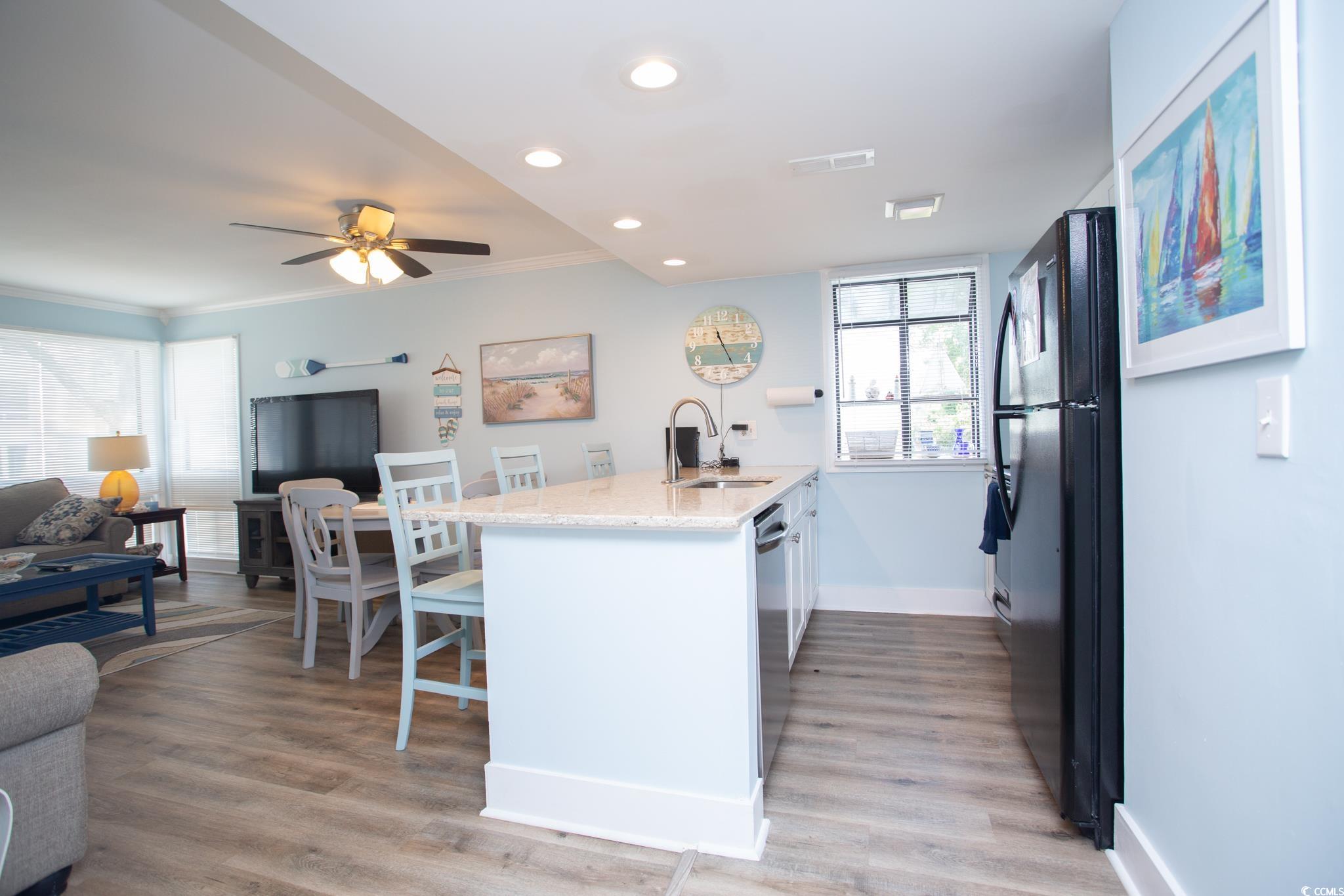 Kitchen with light hardwood / wood-style floors, crown molding, sink, and stainless steel dishwasher