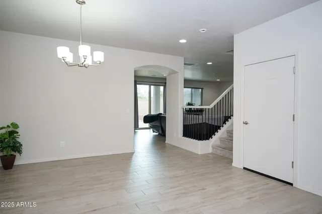 a view of an empty room with wooden floor and kitchen view