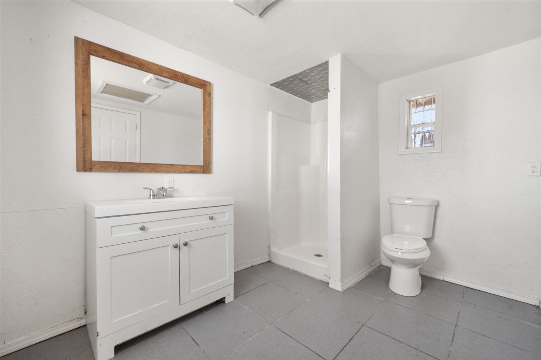 1303 28th Street Lubbock, TX 79411 - Photo 11 of 12 a bathroom with a toilet sink and mirror