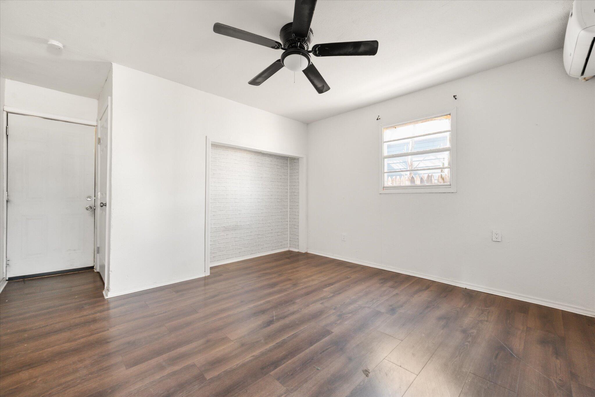1303 28th Street Lubbock, TX 79411 - Photo 9 of 12 an empty room with wooden floor chandelier fan and windows