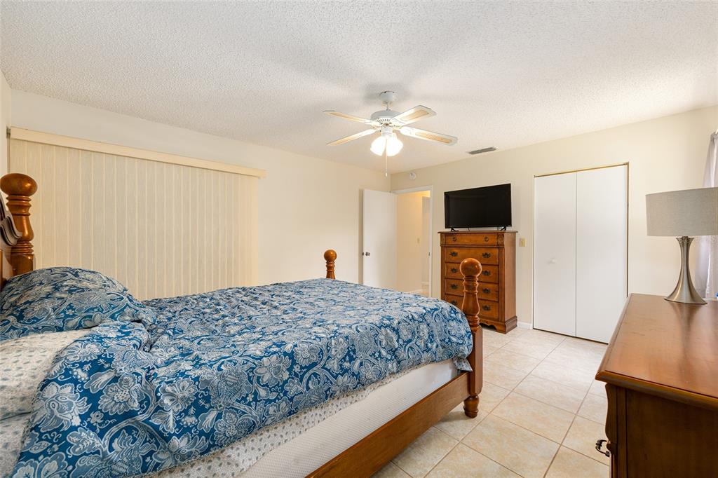 10888 Southwest 90th Court Ocala, FL 34481 - Photo 25 of 37 a bedroom with a bed a chandelier and a television