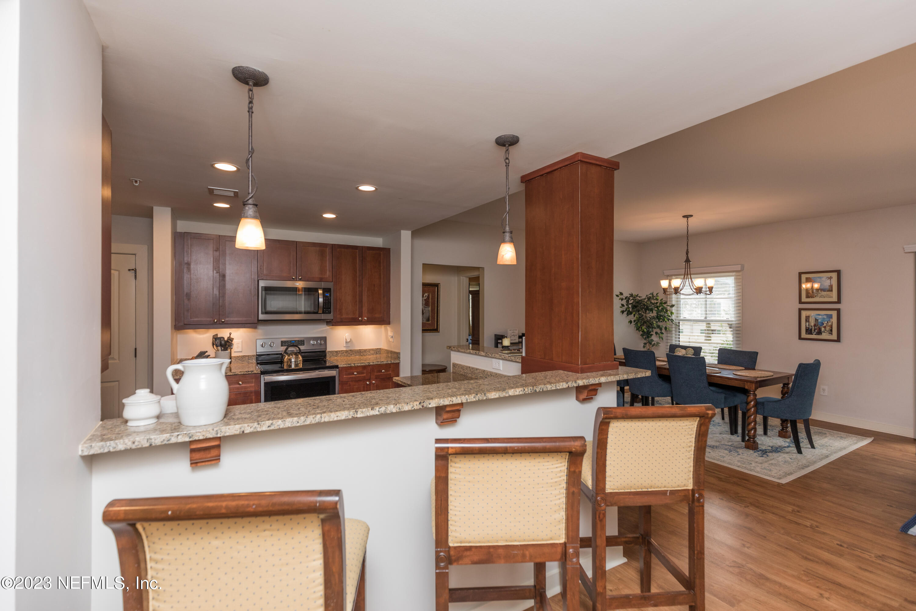 945 Registry Boulevard, Unit 201 St. Augustine, FL 32092 - Photo 40 of 65 a kitchen with stainless steel appliances kitchen island granite countertop a dining table chairs and granite counter tops