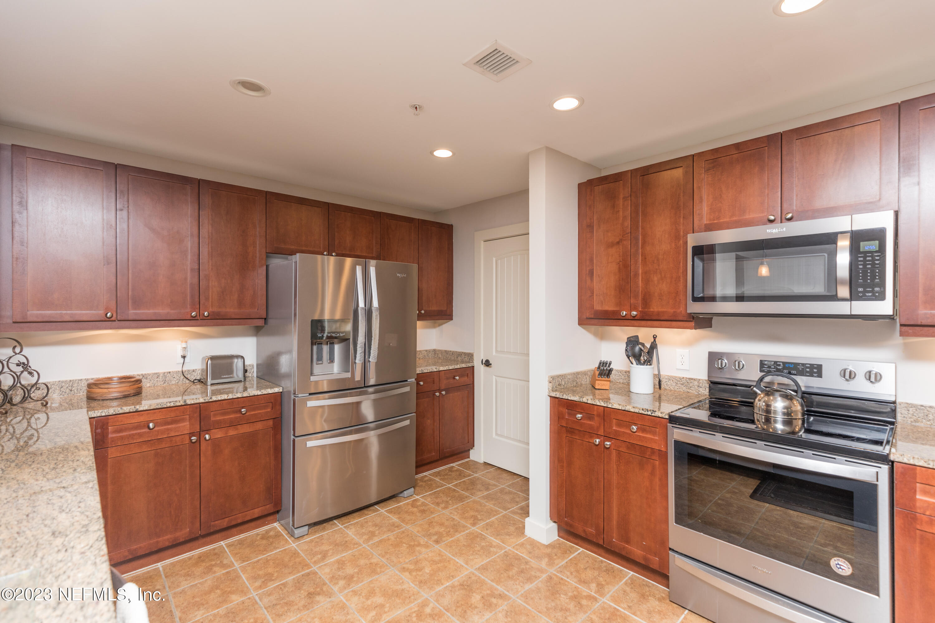 945 Registry Boulevard, Unit 201 St. Augustine, FL 32092 - Photo 50 of 65 a kitchen with stainless steel appliances granite countertop a stove top oven a sink dishwasher a refrigerator and cabinets with wooden floor