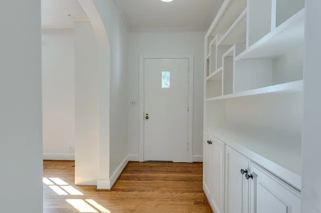 an empty room with wooden floor and windows