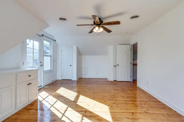 a view of a hallway with wooden floor and a bathroom