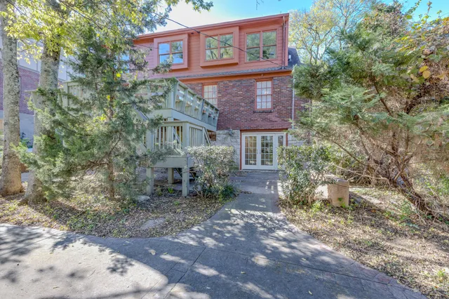 a view of a brick house next to a yard with large trees