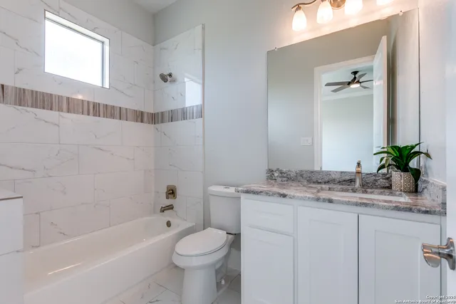 a bathroom with a granite countertop sink a toilet and shower