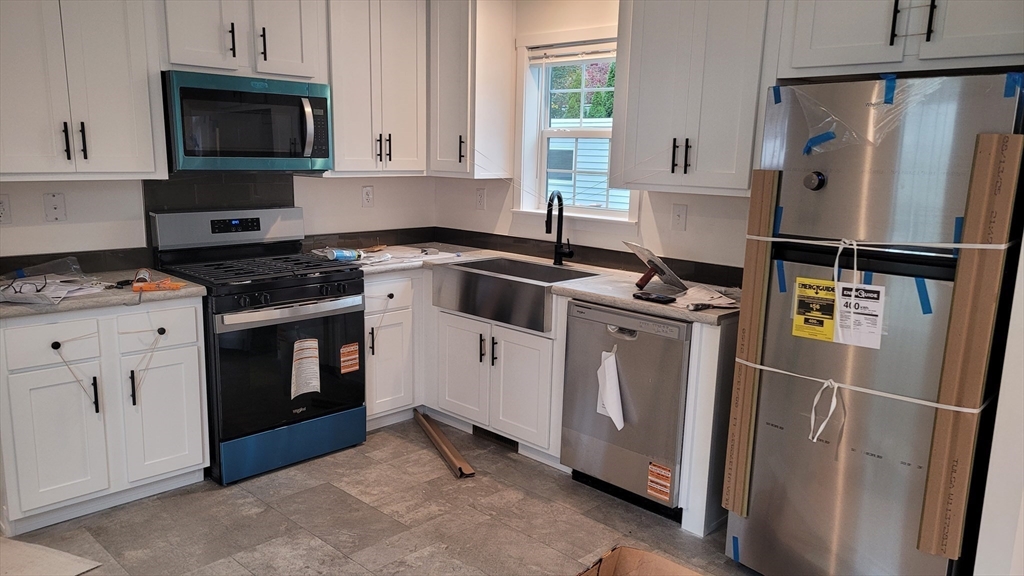 286 Newbury Street, Unit 110 Peabody, MA 01960 - Photo 2 of 15 a kitchen with white cabinets and white appliances