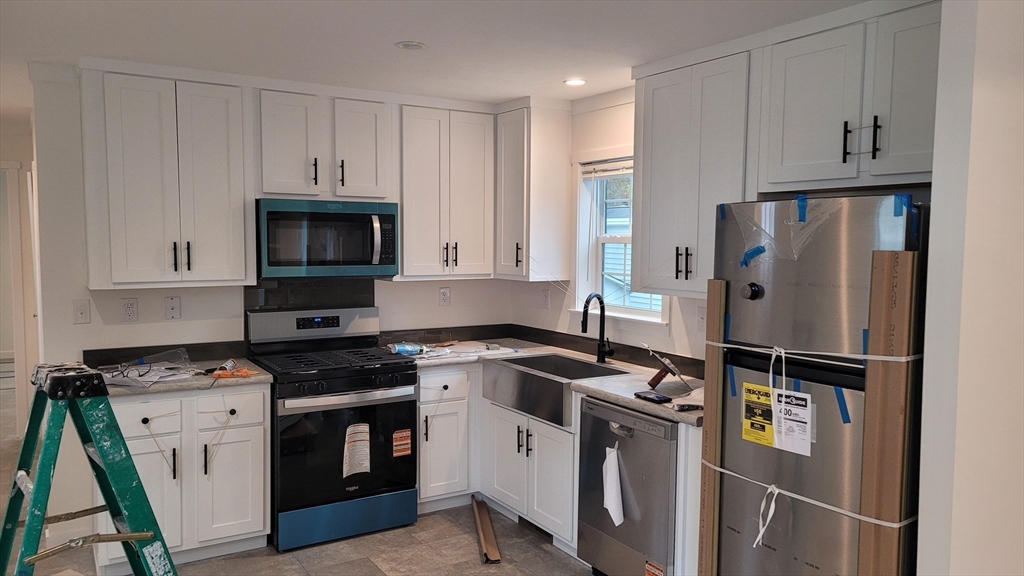 286 Newbury Street, Unit 110 Peabody, MA 01960 - Photo 4 of 15 a kitchen with stainless steel appliances a refrigerator stove and microwave