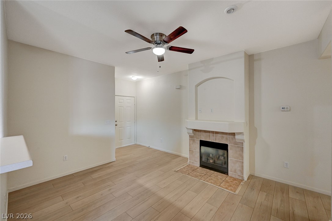 9050 West Warm Springs Road, Unit 1147 Las Vegas, NV 89148 - Photo 5 of 36 A cozy living space features rich hardwood flooring and a charming tiled fireplace.