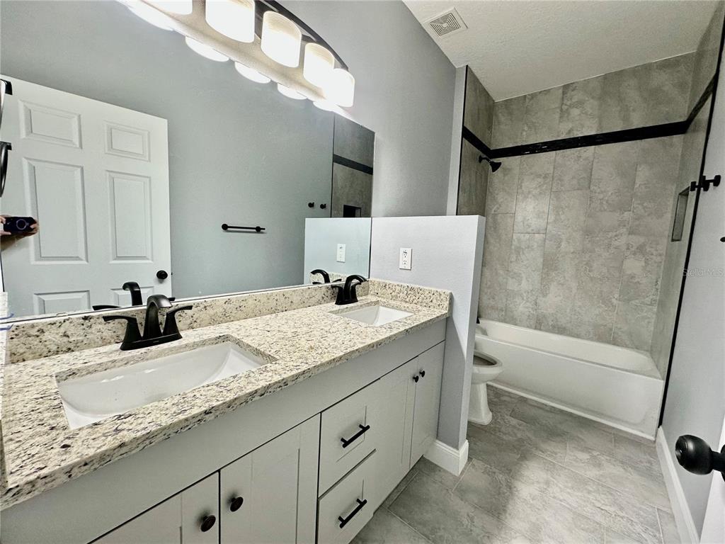 314 15th Avenue Ocoee, FL 34761 - Photo 13 of 37 a bathroom with a granite countertop sink a mirror and a bathtub