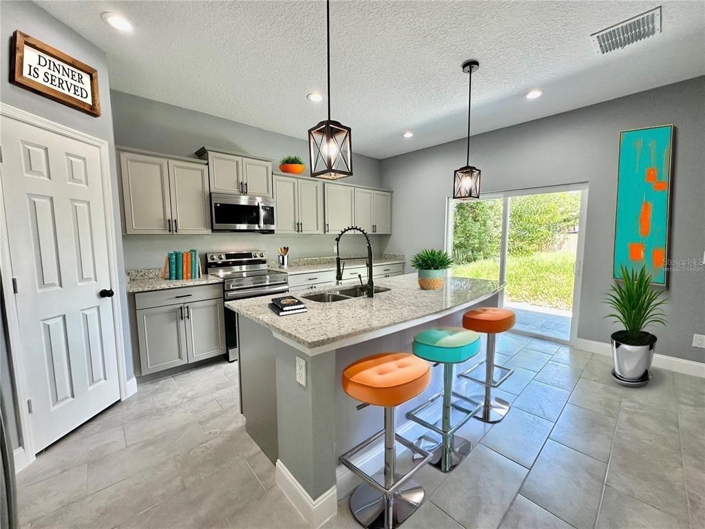 314 15th Avenue Ocoee, FL 34761 - Photo 2 of 37 a kitchen with stainless steel appliances granite countertop a stove a sink a refrigerator a center island a dining table and chairs