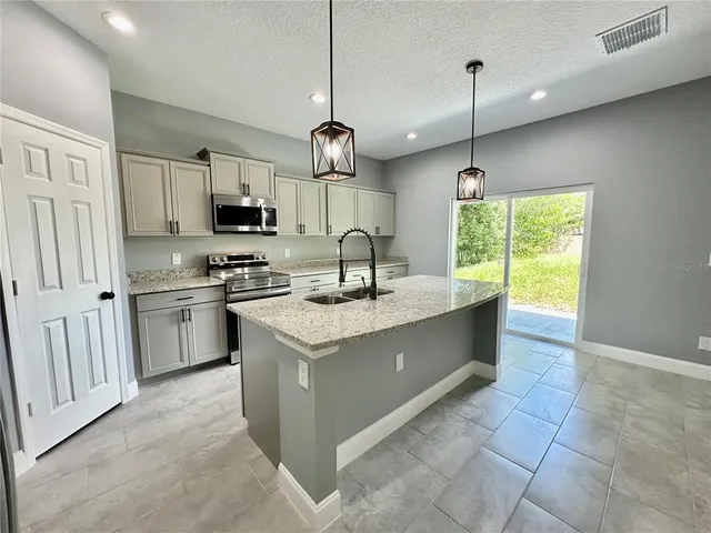 a kitchen with stainless steel appliances granite countertop a sink a stove a refrigerator and island with wooden floor