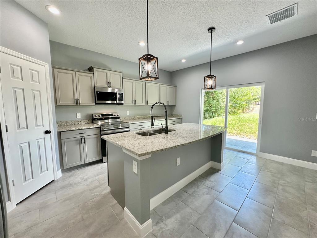 314 15th Avenue Ocoee, FL 34761 - Photo 3 of 37 a kitchen with stainless steel appliances granite countertop a sink a stove a refrigerator and island with wooden floor