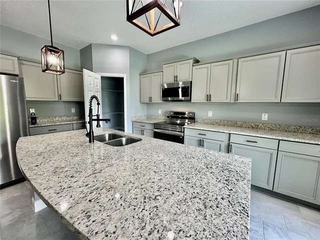 a kitchen with stainless steel appliances granite countertop a sink a stove and cabinets